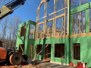 Close-up of a house under construction showing high wall framing, with the first floor wrapped in green ZIP System sheathing