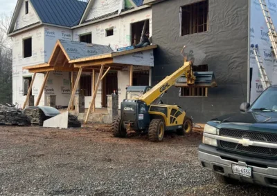 a yellow GEHL telehandler lifting materials, with a pickup truck in the foreground